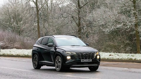Hyundai Tucson hybrid electric car driving on a cold frosty morning