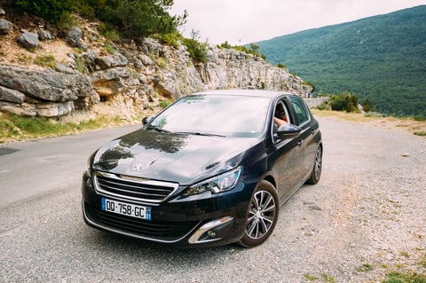 Black Peugeot 308 5-door car on French mountain nature landscape