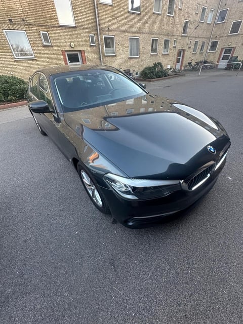 Black BMW sedan parked in front of a brick apartment building in a residential courtyard