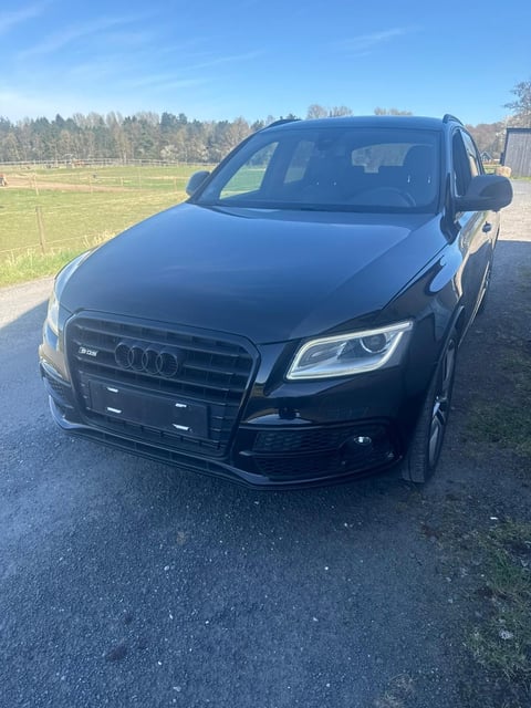 Black Audi Q5 SUV parked on driveway with rural field and trees in background